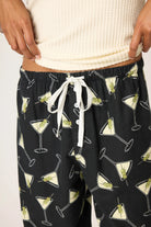 Black pajama pants with martini glass pattern worn by a person.