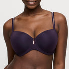 Woman wearing a dark purple bra with a zipper on a plain background