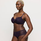 Woman wearing a dark purple bra and underwear set on a white background