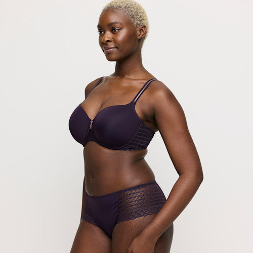Woman wearing a dark purple bra and underwear set on a white background