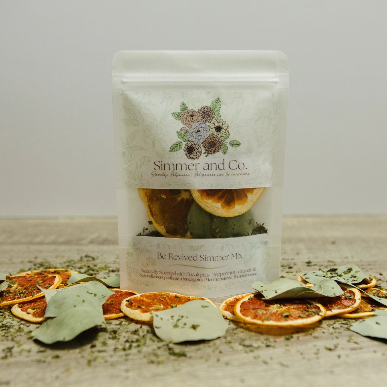 Packaging of 'Simmer and Co.' simmer mix with dried oranges and leaves on a wooden surface.