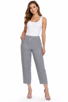 Woman wearing a white sleeveless top and sage linen pants on a white background