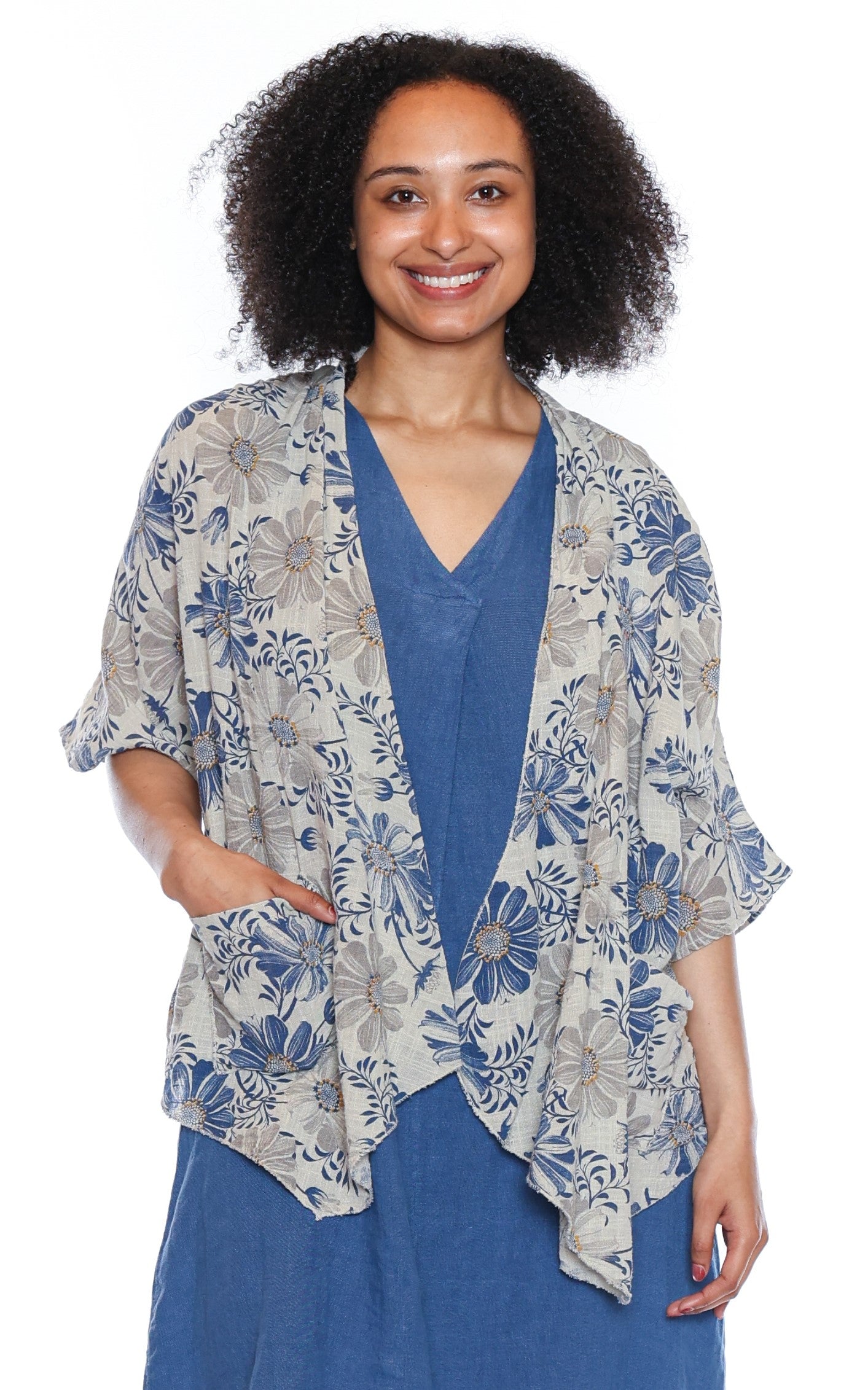 Woman wearing a floral short cardigan over a blue dress on a white background