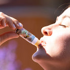Person applying Barefoot Venus lip balm to their lips with a blurred background