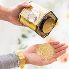 Barefoot Venus Mustard Bath in Yellow Tin container, shown against a white background, tipped on its side with some loose yellow bath salt poured into an outstretched hand.  