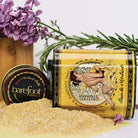 Barefoot Venus Mustard Bath in Yellow Tin container, shown against a white background, tipped on its side with some loose yellow bath salt around the base. 