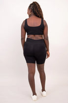 Blue Sky Clipper Top in Black shown on a model against a white background, worn with black shorts from the back view. 