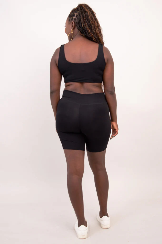 Blue Sky Clipper Top in Black shown on a model against a white background, worn with black shorts from the back view. 