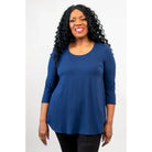Blue Sky Jazz 3/4 Sleeve Top in Indigo shown on a model wearing black leggings standing against a white background, from the front view. 