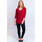 Blue Sky Jazz 3/4 Sleeve Top in Lipstick Red shown on a model wearing black leggings against a white background, from the front view. 