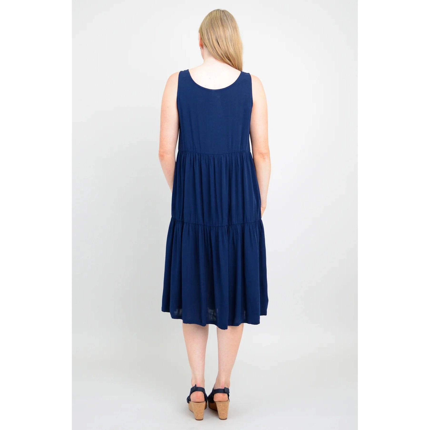 Blue Sky Juni Dress in Indigo shown on a model against a white background, from the back view. 
