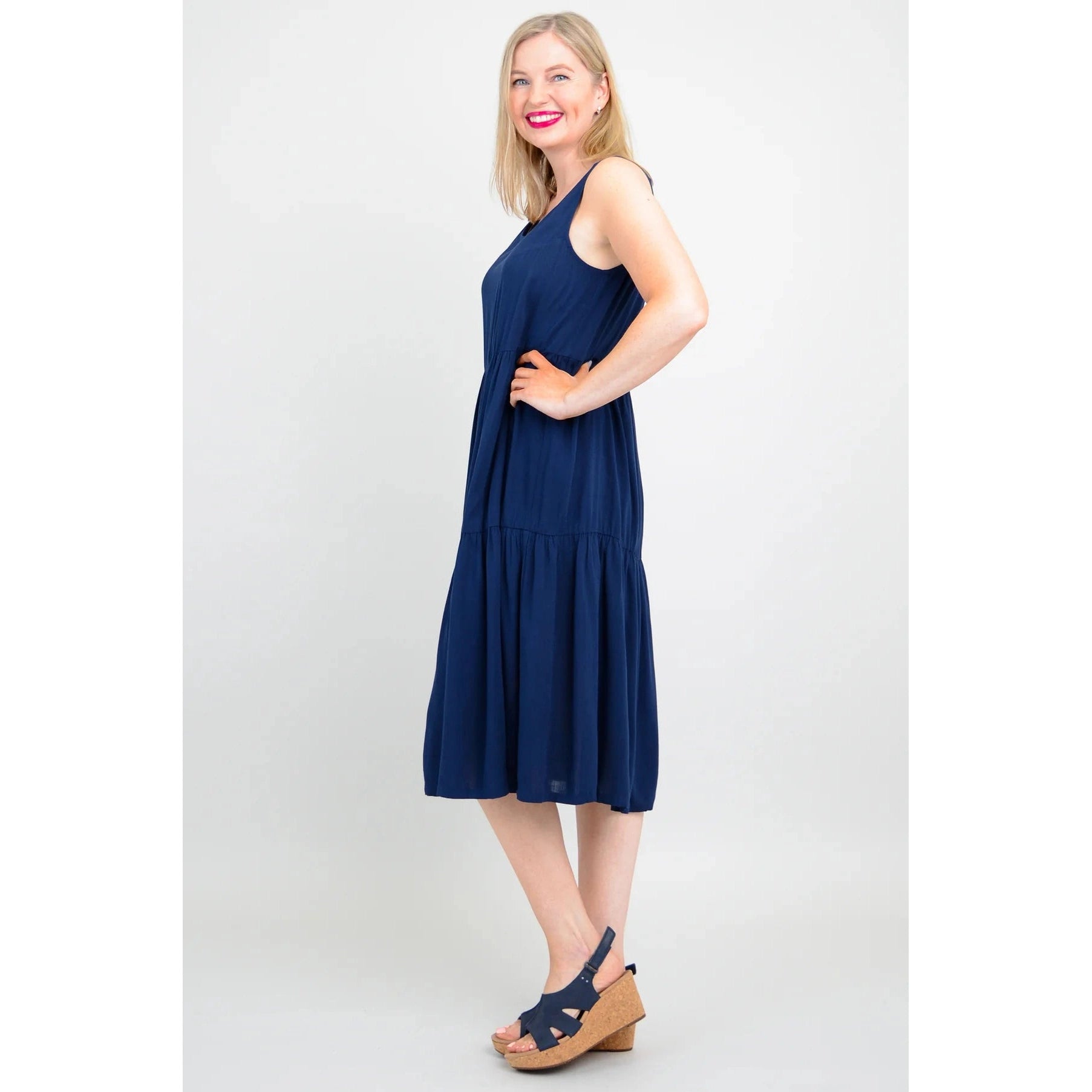 Blue Sky Juni Dress in Indigo shown on a model against a white background, from the side view. 