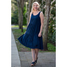 Blue Sky Juni Dress in Indigo shown on a model against an outdoor background, from the front view. 