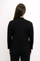 Blue Sky Kathy Jacket in Black shown on a model wearing it over a white tank with black pants against a white background, shown from the back. 
