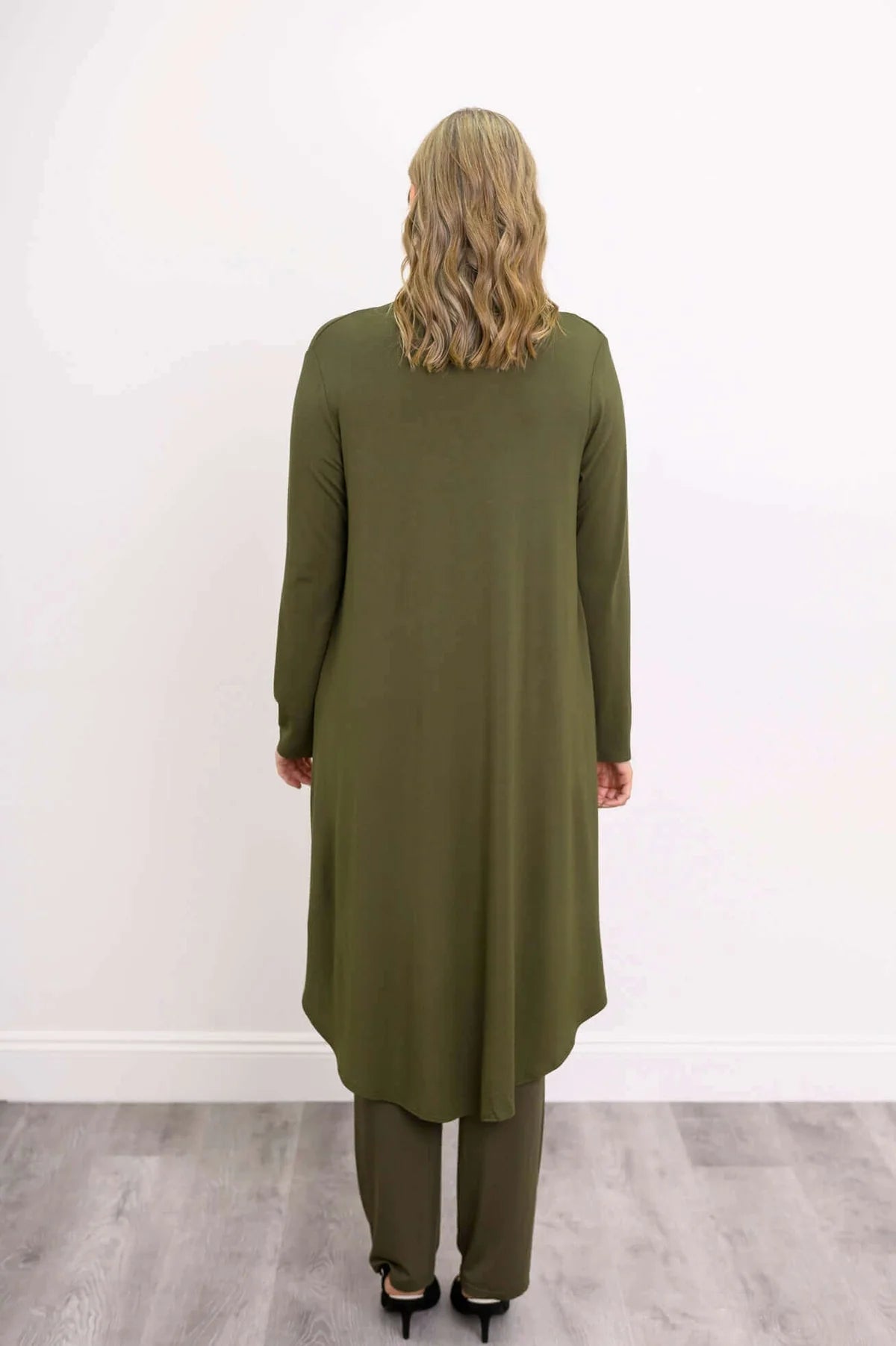 Blue Sky Priscilla Jacket in Khaki shown on a model wearing a white tank and khaki pants, standing against a white background, from the back view. 