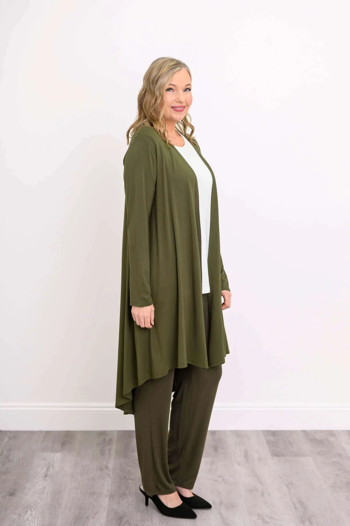 Blue Sky Priscilla Jacket in Khaki shown on a model wearing a white tank and khaki pants, standing against a white background, from the side view. 