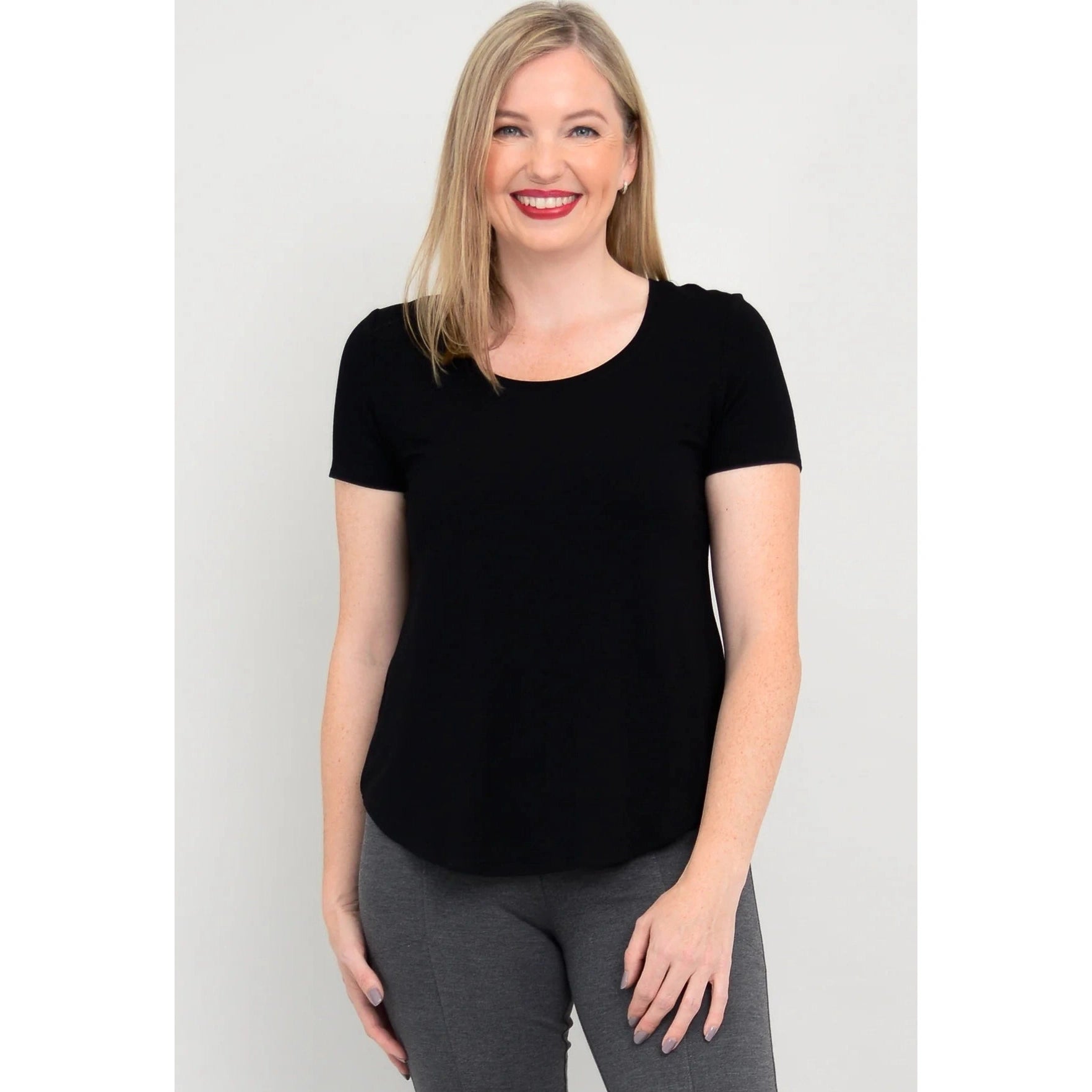 Blue Sky Tessa Tee in Black shown on a model wearing grey leggings standing against a white background, from the front view. 