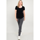 Blue Sky Tessa Tee in Black shown on a model wearing grey leggings standing against a white background, from the front view. 