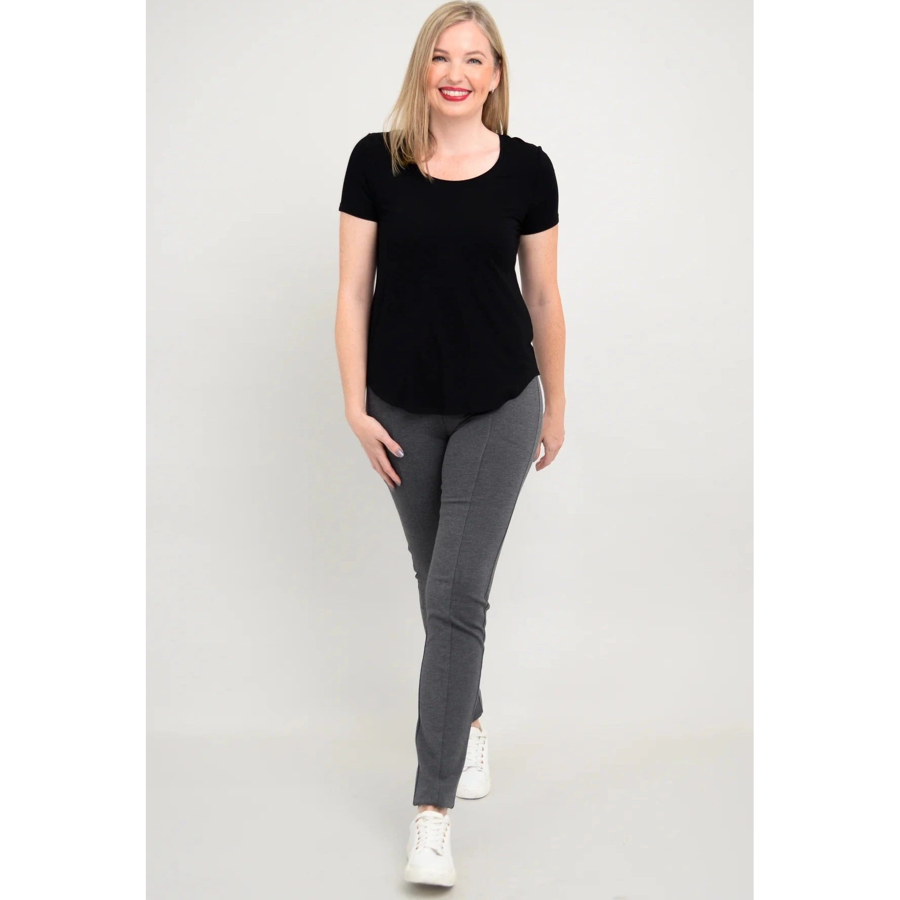 Blue Sky Tessa Tee in Black shown on a model wearing grey leggings standing against a white background, from the front view. 