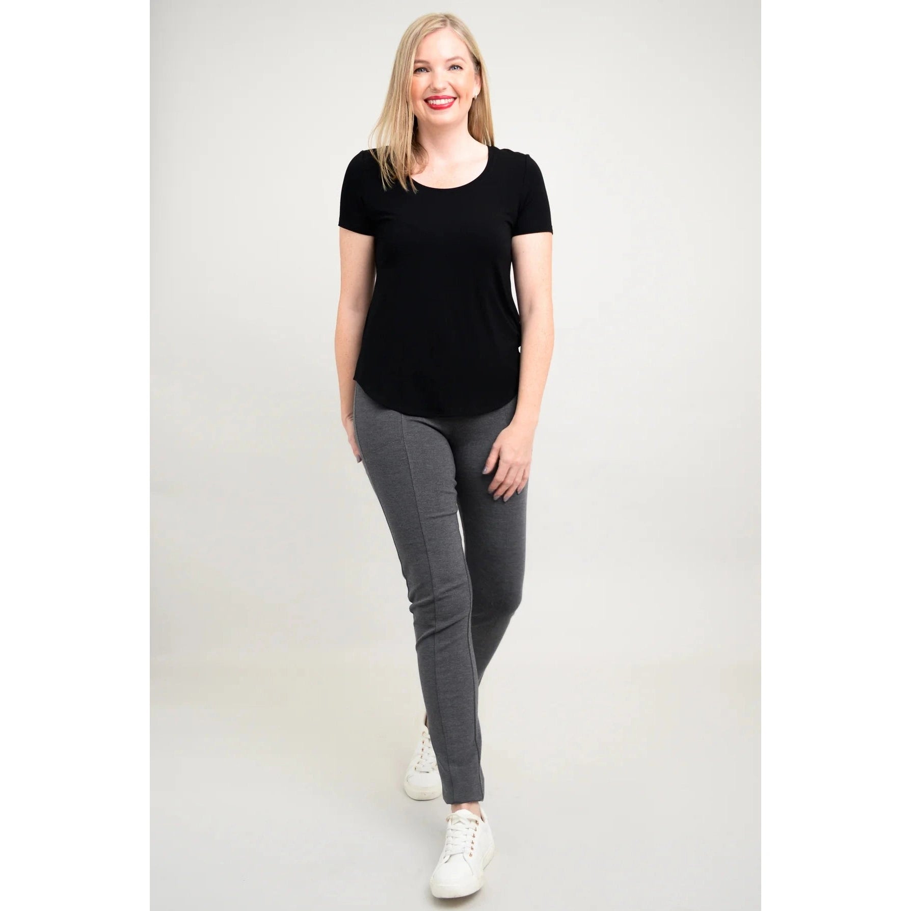 Blue Sky Tessa Tee in Black shown on a model wearing grey leggings standing against a white background, from the front view. 