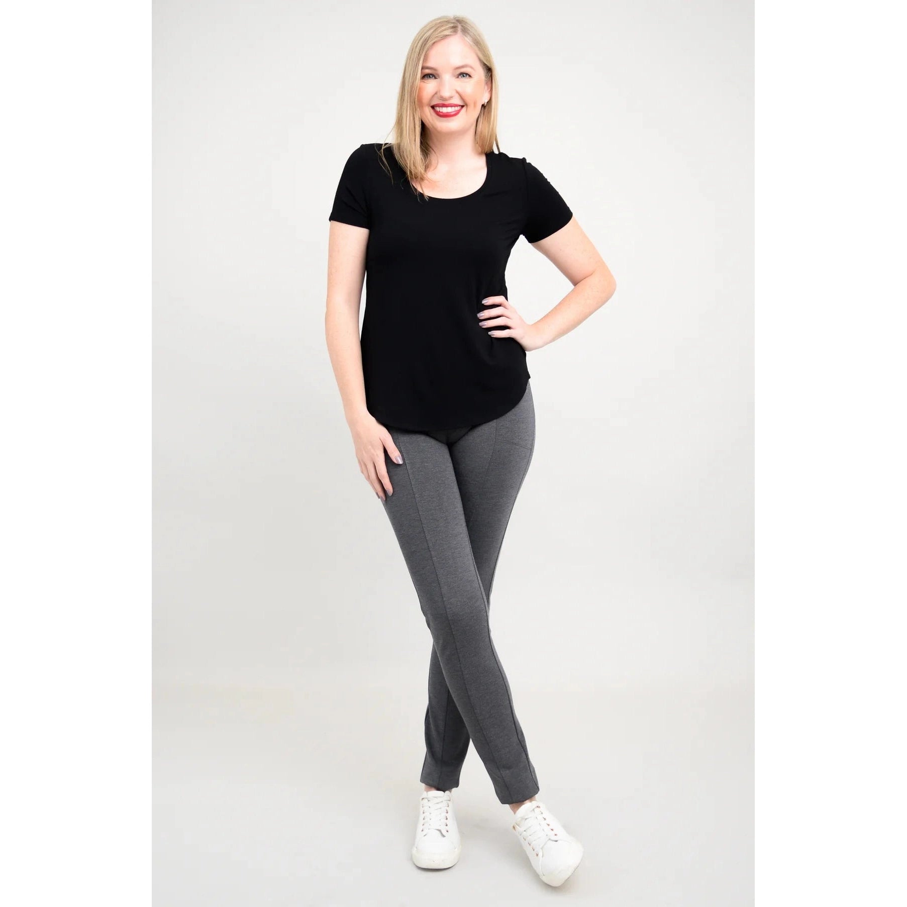 Blue Sky Tessa Tee in Black shown on a model wearing grey leggings standing against a white background, from the front view. 