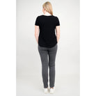 Blue Sky Tessa Tee in Black shown on a model wearing grey leggings standing against a white background, from the back view. 