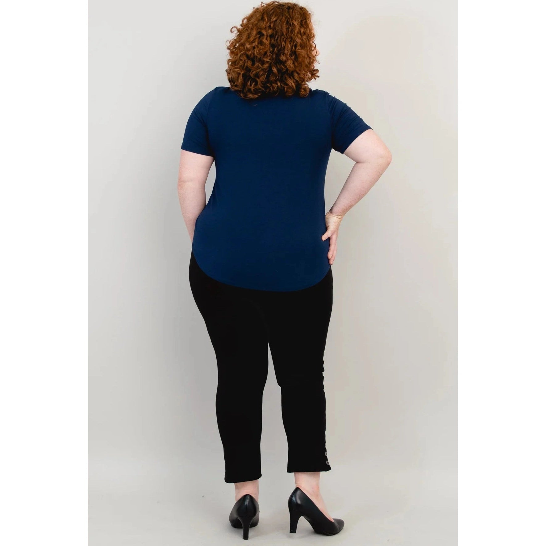 Blue Sky Tessa Tee in Indigo shown on a model wearing black leggings standing against a white background, from the back view. 