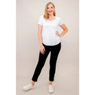 Blue Sky Tessa Tee in white shown on a model wearing black leggings, standing against a white background, from the front view. 