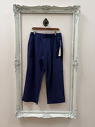 Navy blue pants on a hanger inside an ornate silver frame.
