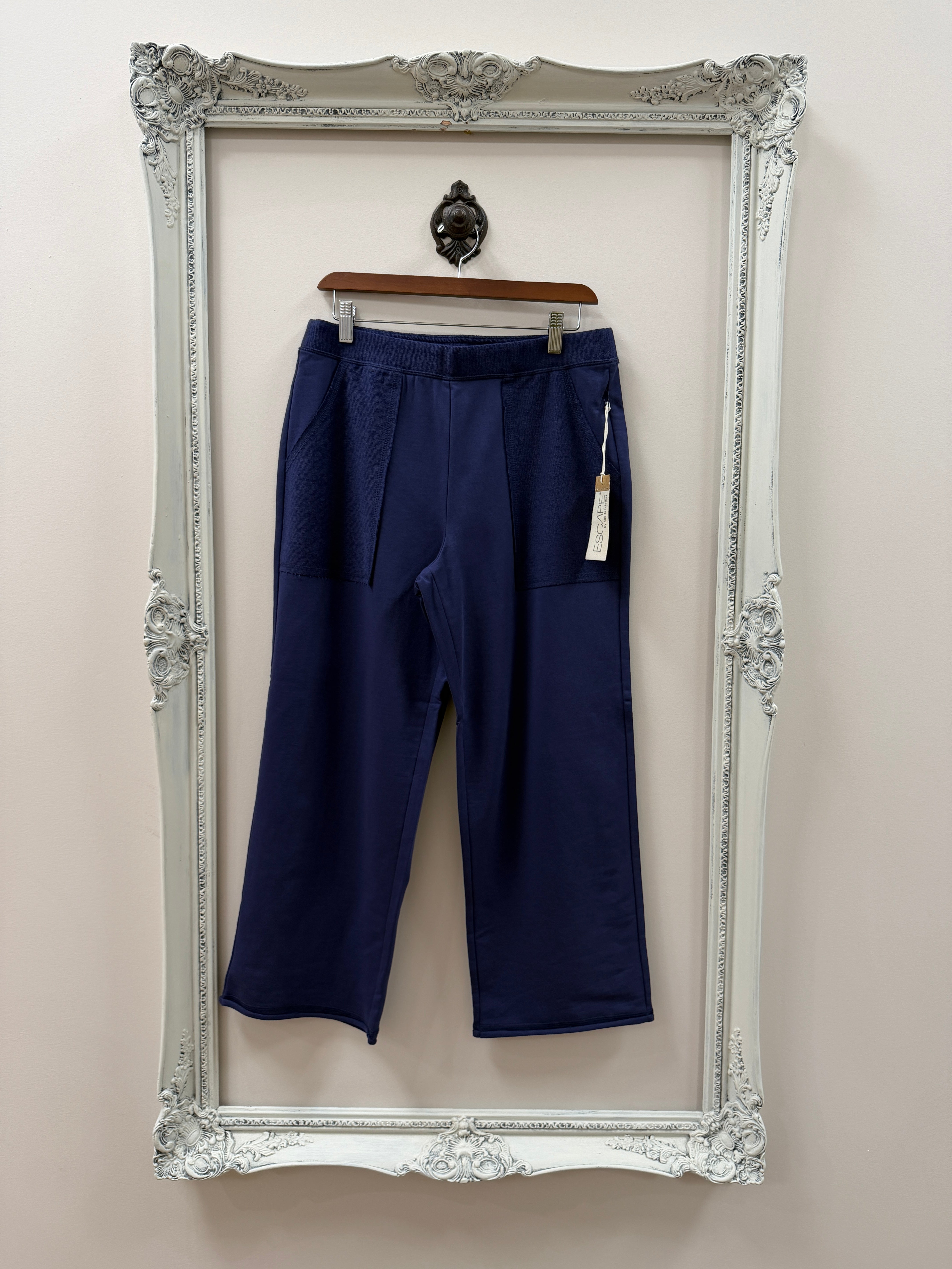Navy blue pants on a hanger inside an ornate silver frame.