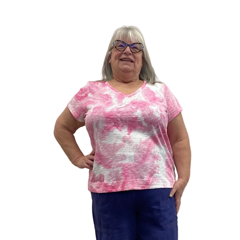 Woman wearing the Escape V Neck Tee in Cosmo pink and white paired with a navy pant against a white background. 