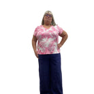 Woman wearing the Escape V Neck Tee in Cosmo pink and white paired with a navy pant against a white background. 