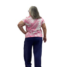 Woman wearing the Escape V Neck Tee in Cosmo pink and white paired with a navy pant against a white background. 