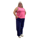 Woman wearing Escape Beach Flood pants in navy with pink tank against white background. 