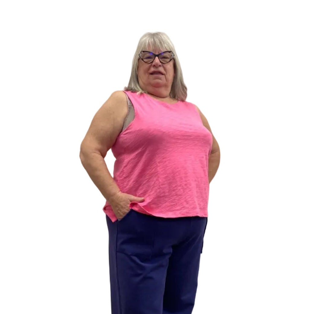 Woman wearing the Escape Crew Tank in Cosmo pink paired with navy pants against a white background. 