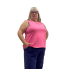 Woman wearing the Escape Crew Tank in Cosmo pink paired with navy pants against a white background. 