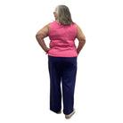 Woman wearing the Escape Crew Tank in Cosmo pink paired with navy pants against a white background. 