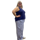 Woman wearing the Escape Getaway Tank in Navy against a white wall, paired with blue and white striped pants. 
