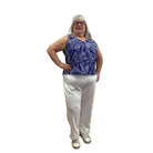 Woman wearing Escape Pocket Trousers in white, paired with a navy and white floral tank, against a white background. 