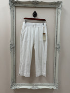 White pants on a hanger inside an ornate silver frame against a plain wall.