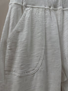 Close-up of white pants with a pocket detail on a light gray background