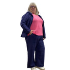 Woman wearing a navy zip up Escape Solstice Hoodie over a pink shirt and with navy pants on a white background. 