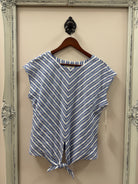 Blue and white striped top on a hanger against a beige wall.