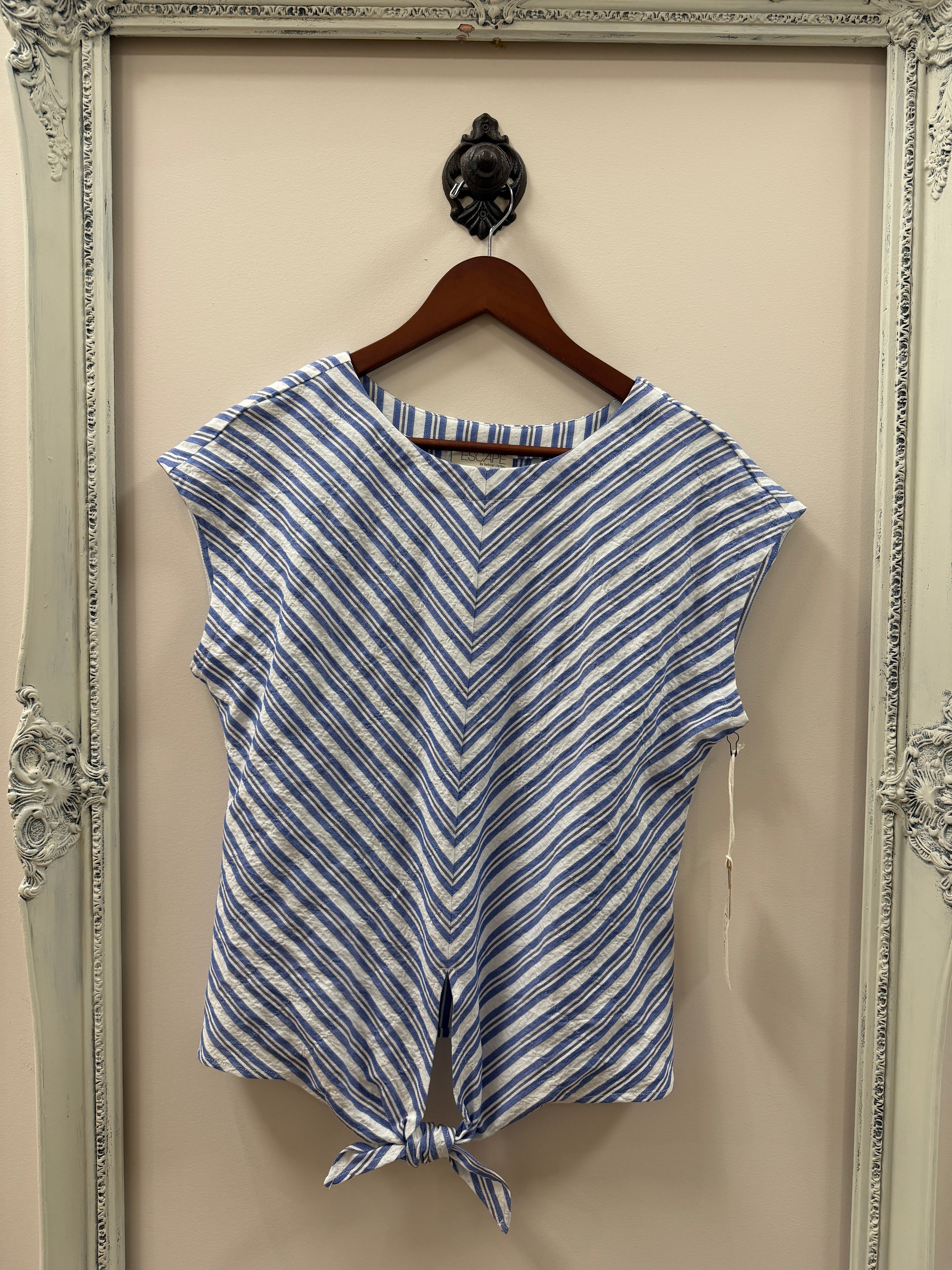 Blue and white striped top on a hanger against a beige wall.